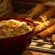 A bowl containing cream filling and a cookie rack filled with thin waffle cookies rolled into cones